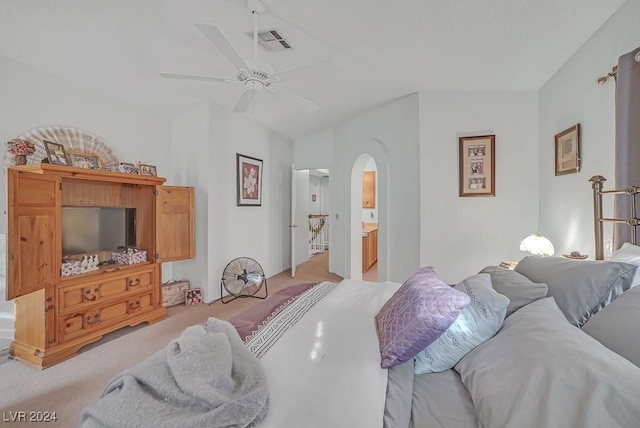 bedroom featuring ensuite bath, ceiling fan, light carpet, and lofted ceiling