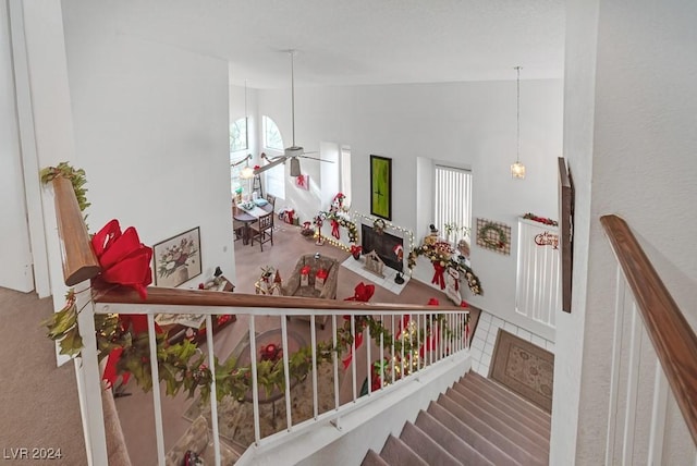 stairs with ceiling fan and high vaulted ceiling