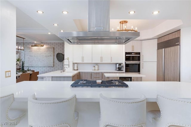 kitchen with island range hood, black double oven, sink, decorative light fixtures, and white cabinets