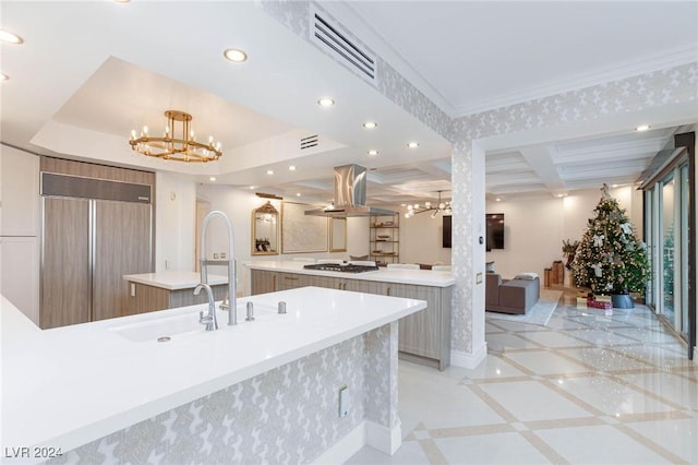 kitchen featuring stainless steel gas stovetop, ornamental molding, a kitchen island, island exhaust hood, and a chandelier