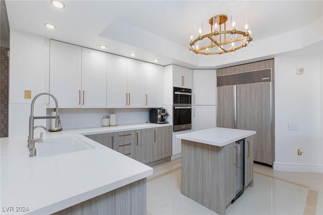 kitchen with a center island, sink, hanging light fixtures, paneled refrigerator, and double oven