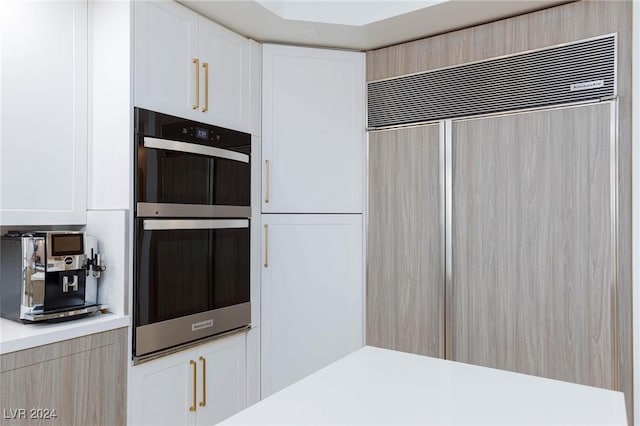 kitchen featuring white cabinets, double oven, and paneled built in fridge