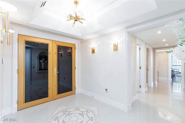 corridor with a chandelier, french doors, light tile patterned floors, and a raised ceiling