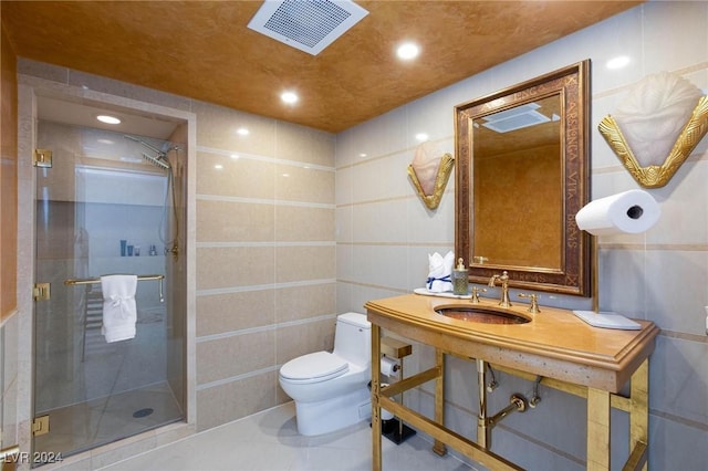 bathroom featuring toilet, sink, a shower with door, and tile walls