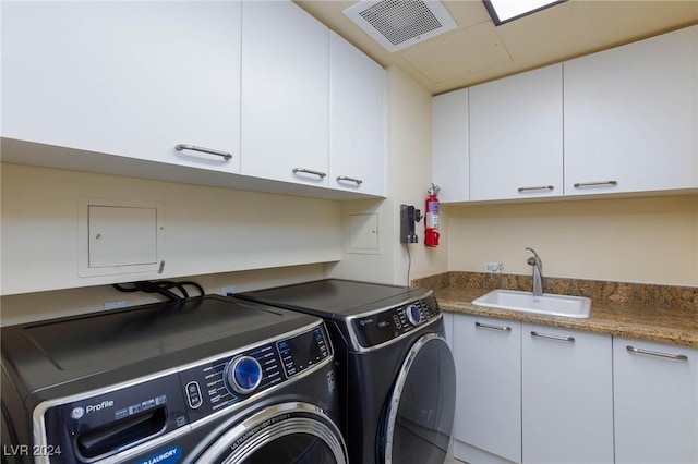 laundry room with cabinets, washing machine and dryer, and sink