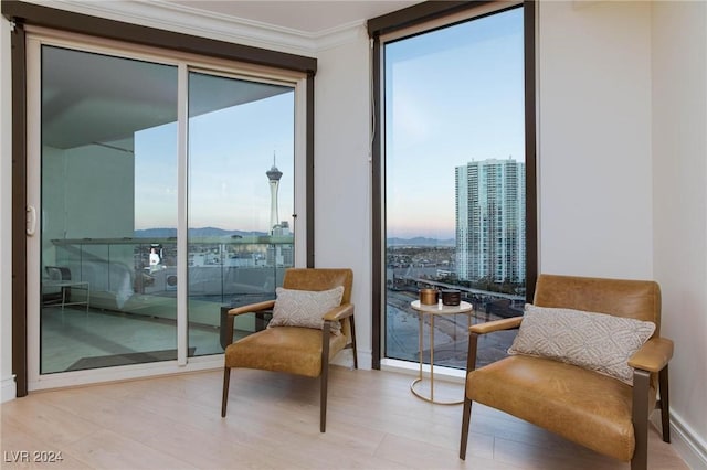 sitting room with light hardwood / wood-style floors, expansive windows, and ornamental molding