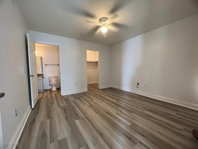 unfurnished bedroom featuring ceiling fan, ensuite bathroom, light hardwood / wood-style floors, a walk in closet, and a closet