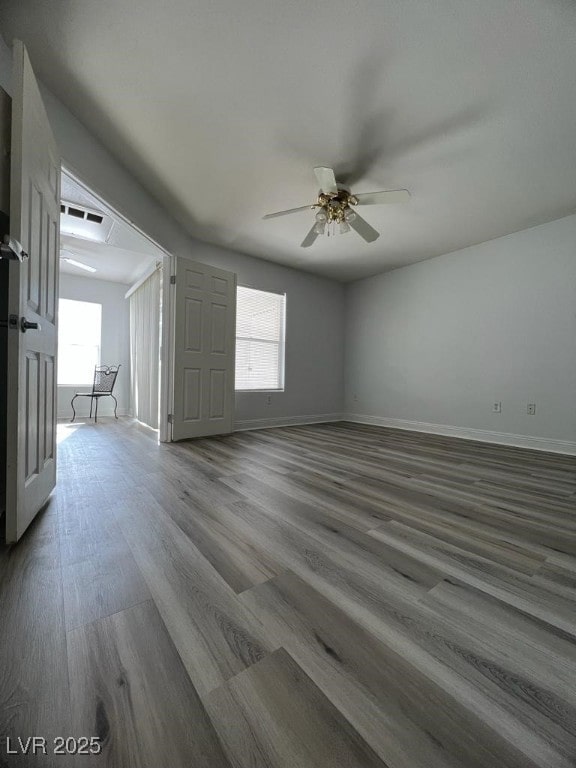 empty room featuring ceiling fan, plenty of natural light, and hardwood / wood-style floors