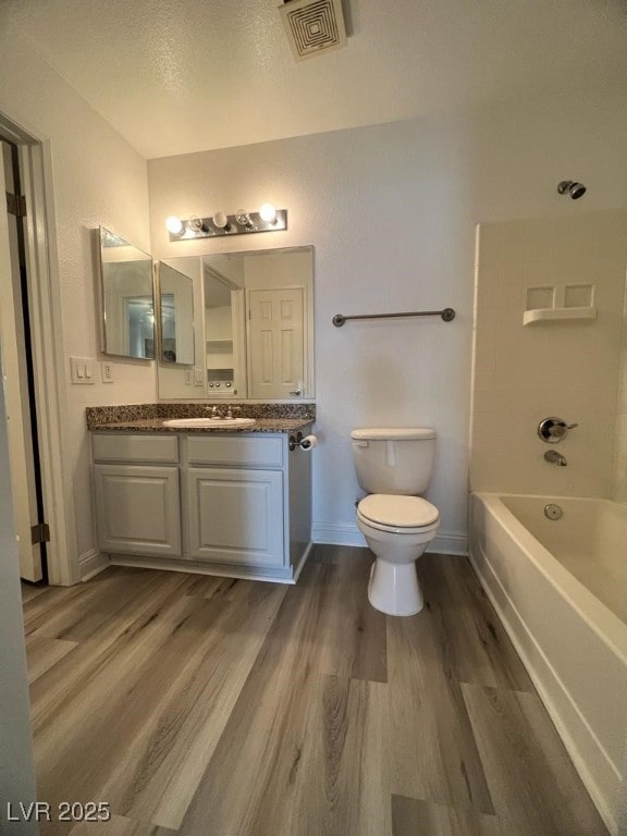 full bathroom with vanity, a textured ceiling, shower / tub combination, hardwood / wood-style floors, and toilet