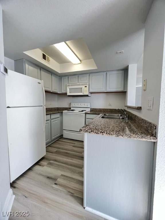 kitchen featuring kitchen peninsula, light wood-type flooring, white appliances, sink, and gray cabinets