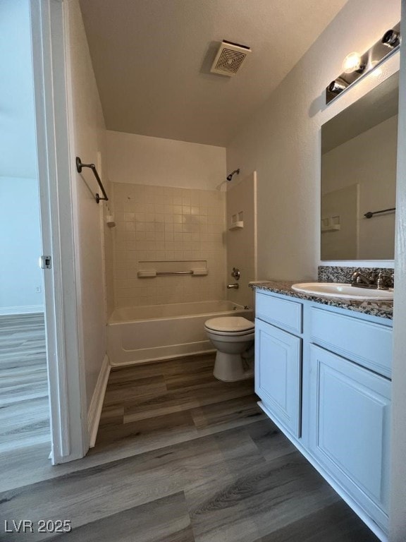 full bathroom featuring toilet, vanity, wood-type flooring, and tiled shower / bath