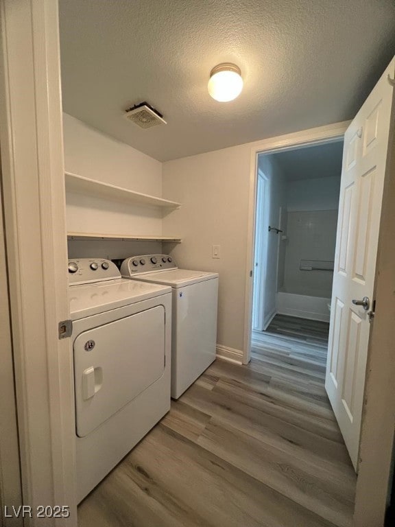 washroom with separate washer and dryer, a textured ceiling, and hardwood / wood-style flooring