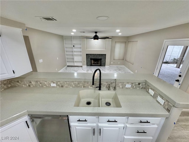 kitchen with white cabinets, sink, ceiling fan, a fireplace, and kitchen peninsula