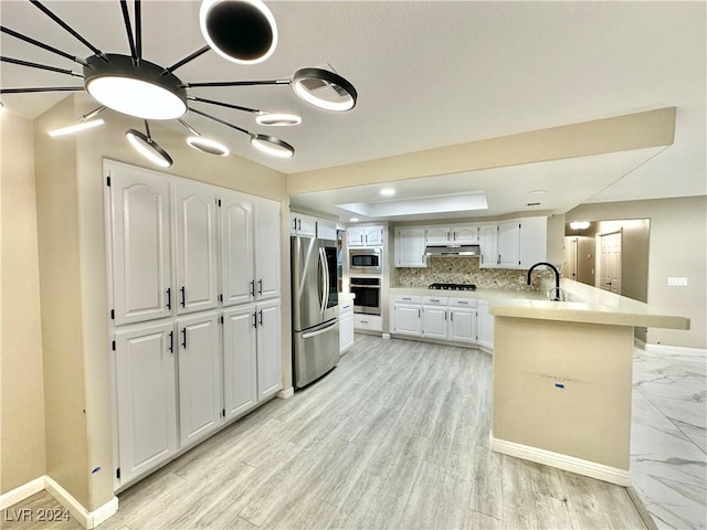 kitchen with white cabinets, sink, decorative backsplash, appliances with stainless steel finishes, and kitchen peninsula