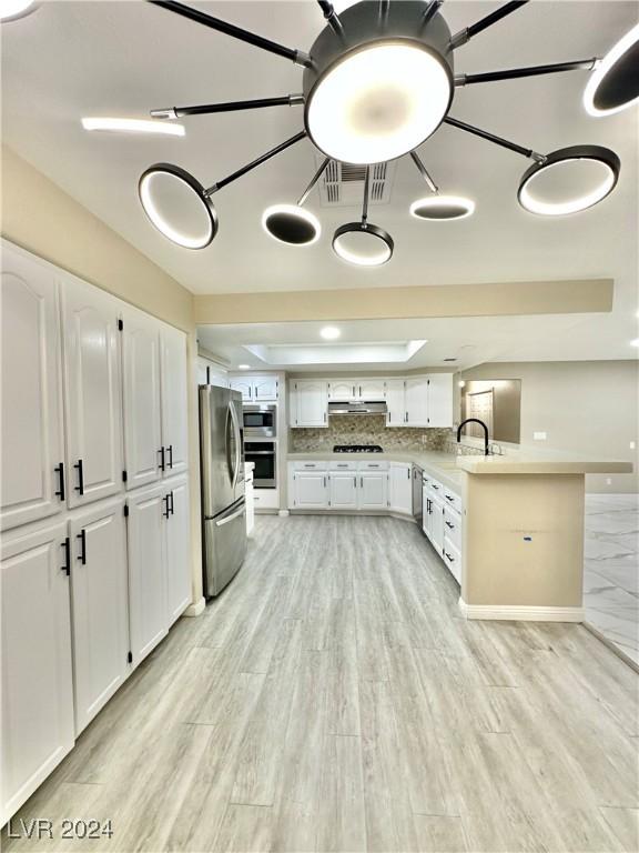 kitchen with white cabinets, light wood-type flooring, and stainless steel appliances