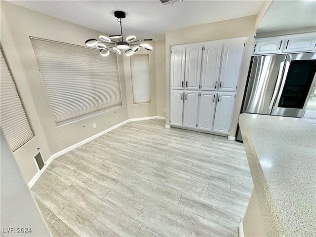 unfurnished dining area featuring light wood-type flooring and a chandelier