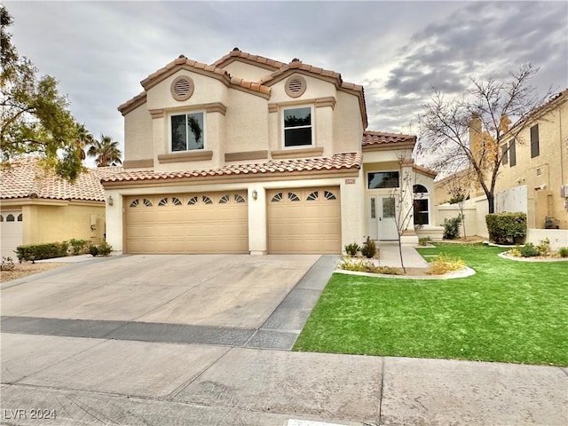 mediterranean / spanish house with a garage and a front lawn