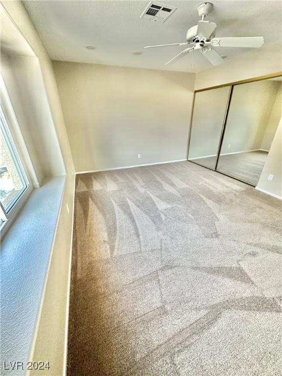 unfurnished bedroom featuring carpet flooring, ceiling fan, and a closet