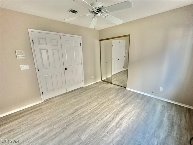 unfurnished bedroom featuring two closets, light hardwood / wood-style floors, and ceiling fan