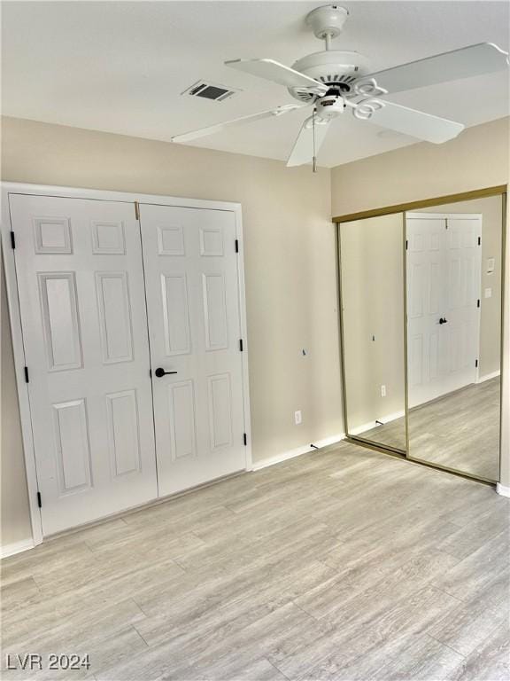 unfurnished bedroom featuring multiple closets, ceiling fan, and light wood-type flooring