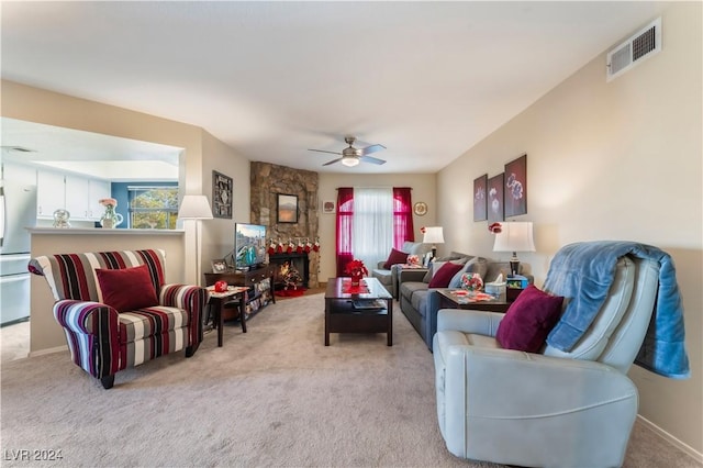 carpeted living room featuring ceiling fan and a fireplace