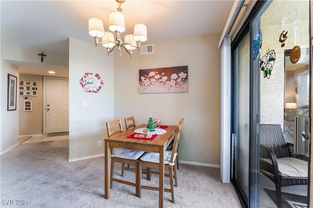 dining area featuring light colored carpet and an inviting chandelier