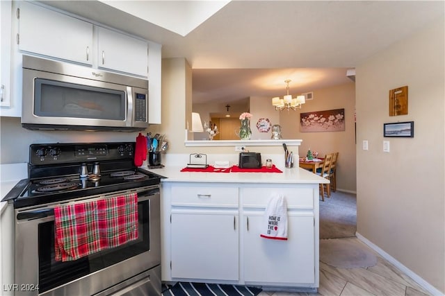 kitchen with an inviting chandelier, hanging light fixtures, kitchen peninsula, appliances with stainless steel finishes, and white cabinetry