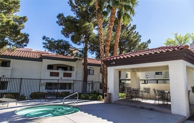 rear view of property with a community hot tub and a patio