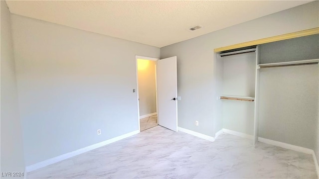 unfurnished bedroom with a textured ceiling and a closet