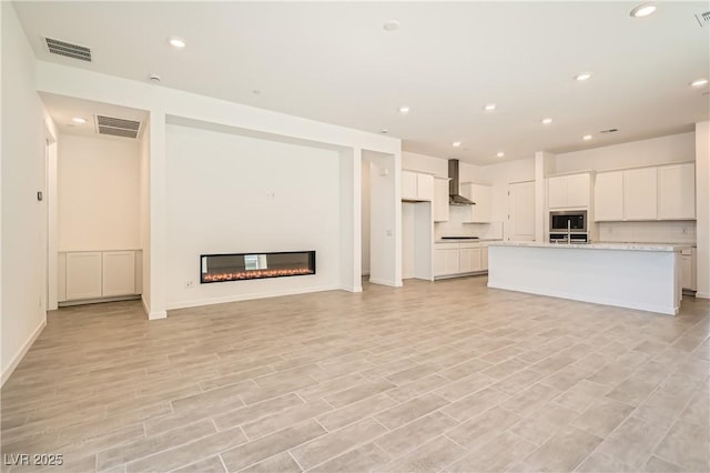 106 Barkset Way, Henderson, NV 89011 - unfurnished living room with a glass covered fireplace, recessed lighting, light wood-type flooring, and baseboards