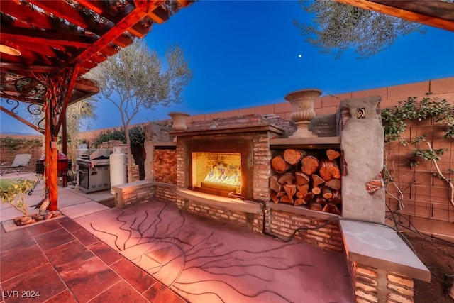 patio terrace at dusk with area for grilling and exterior fireplace