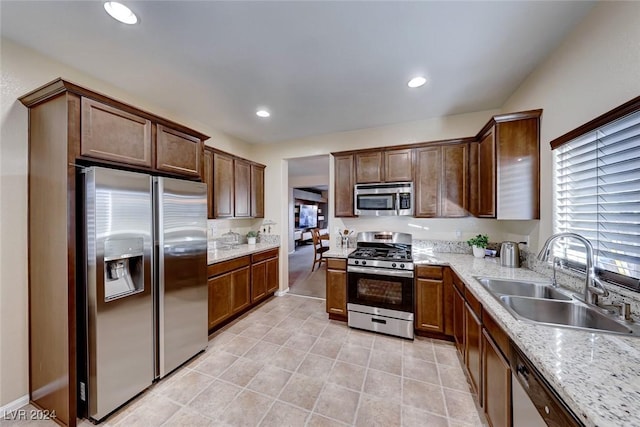 kitchen with light stone countertops, stainless steel appliances, and sink