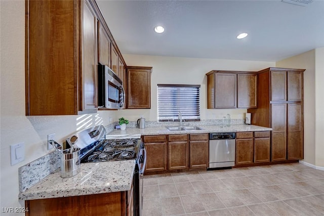 kitchen with light stone counters, sink, and appliances with stainless steel finishes