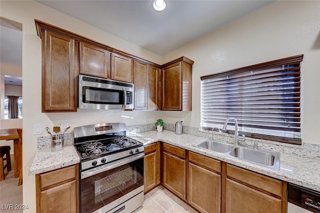 kitchen with light stone counters, sink, and appliances with stainless steel finishes