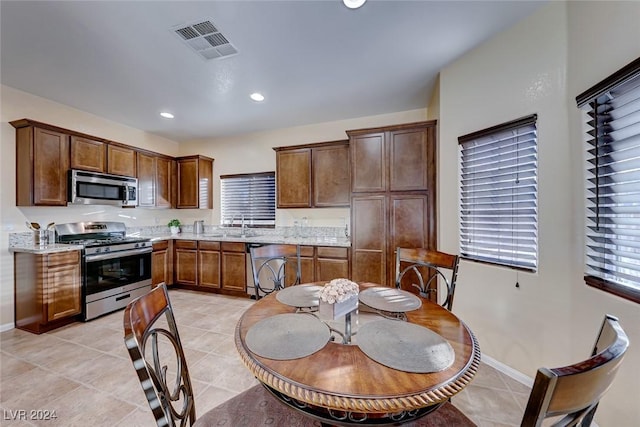 kitchen with light stone countertops, sink, light tile patterned floors, and appliances with stainless steel finishes