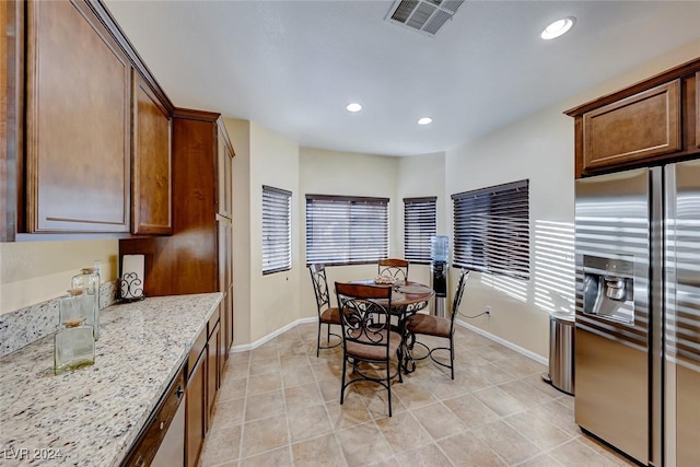 kitchen featuring stainless steel fridge, light tile patterned flooring, and light stone countertops