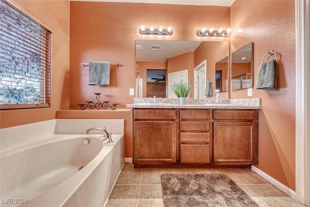 bathroom featuring vanity, tiled bath, and ceiling fan