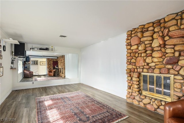 unfurnished living room with hardwood / wood-style floors and a stone fireplace