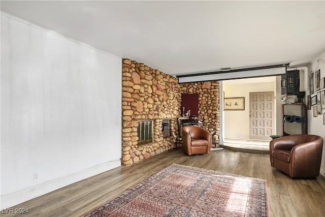 living room with a large fireplace, wood-type flooring, and ornamental molding