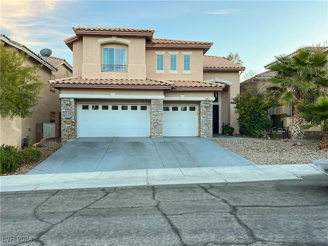 mediterranean / spanish-style home with stone siding, concrete driveway, an attached garage, and stucco siding