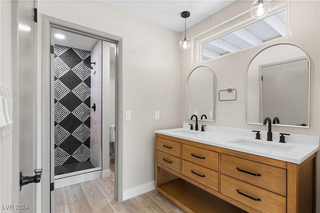 bathroom featuring tiled shower, vanity, hardwood / wood-style flooring, and toilet