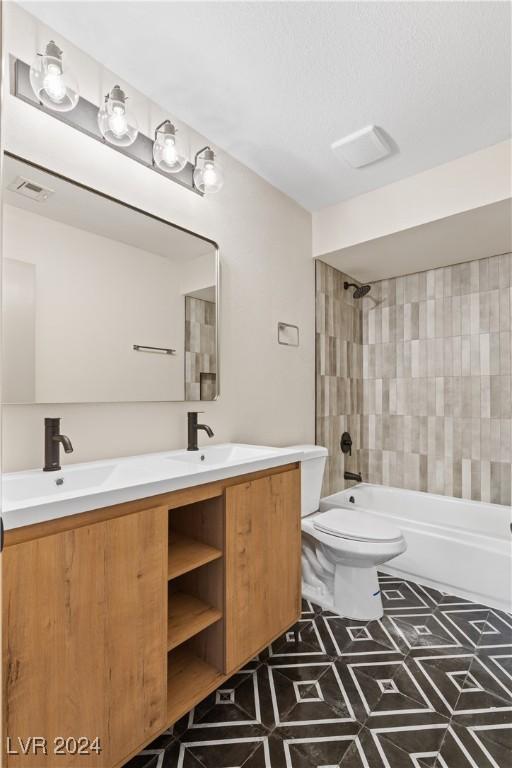 full bathroom with vanity, tile patterned floors, tiled shower / bath combo, and toilet