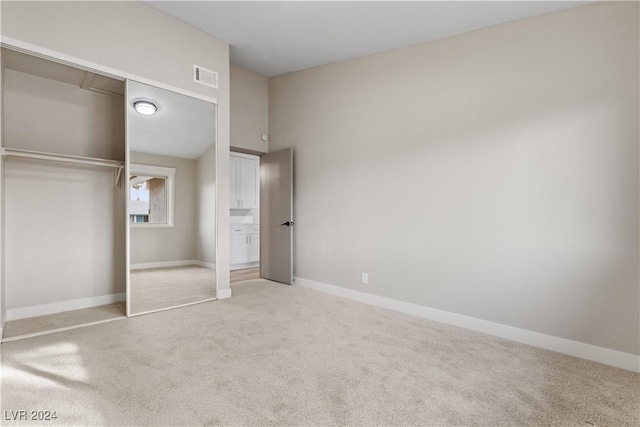 unfurnished bedroom with light carpet and a closet