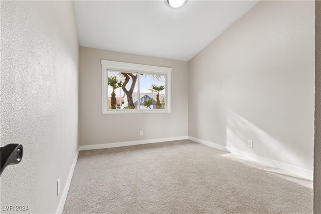 carpeted empty room with lofted ceiling