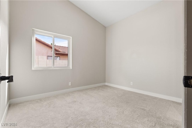 carpeted spare room featuring lofted ceiling