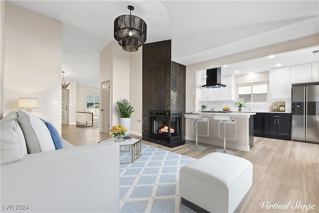 living room featuring a notable chandelier, a multi sided fireplace, and light wood-type flooring