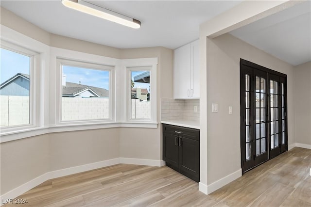 kitchen featuring white cabinets, decorative backsplash, french doors, and light hardwood / wood-style flooring