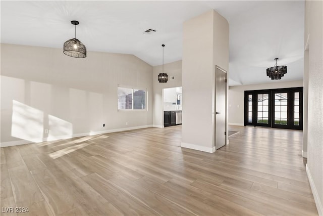 unfurnished living room with light hardwood / wood-style floors, an inviting chandelier, and vaulted ceiling