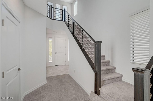 stairs featuring carpet floors and a high ceiling