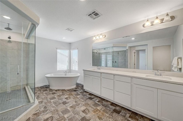 bathroom with vanity, independent shower and bath, and a textured ceiling